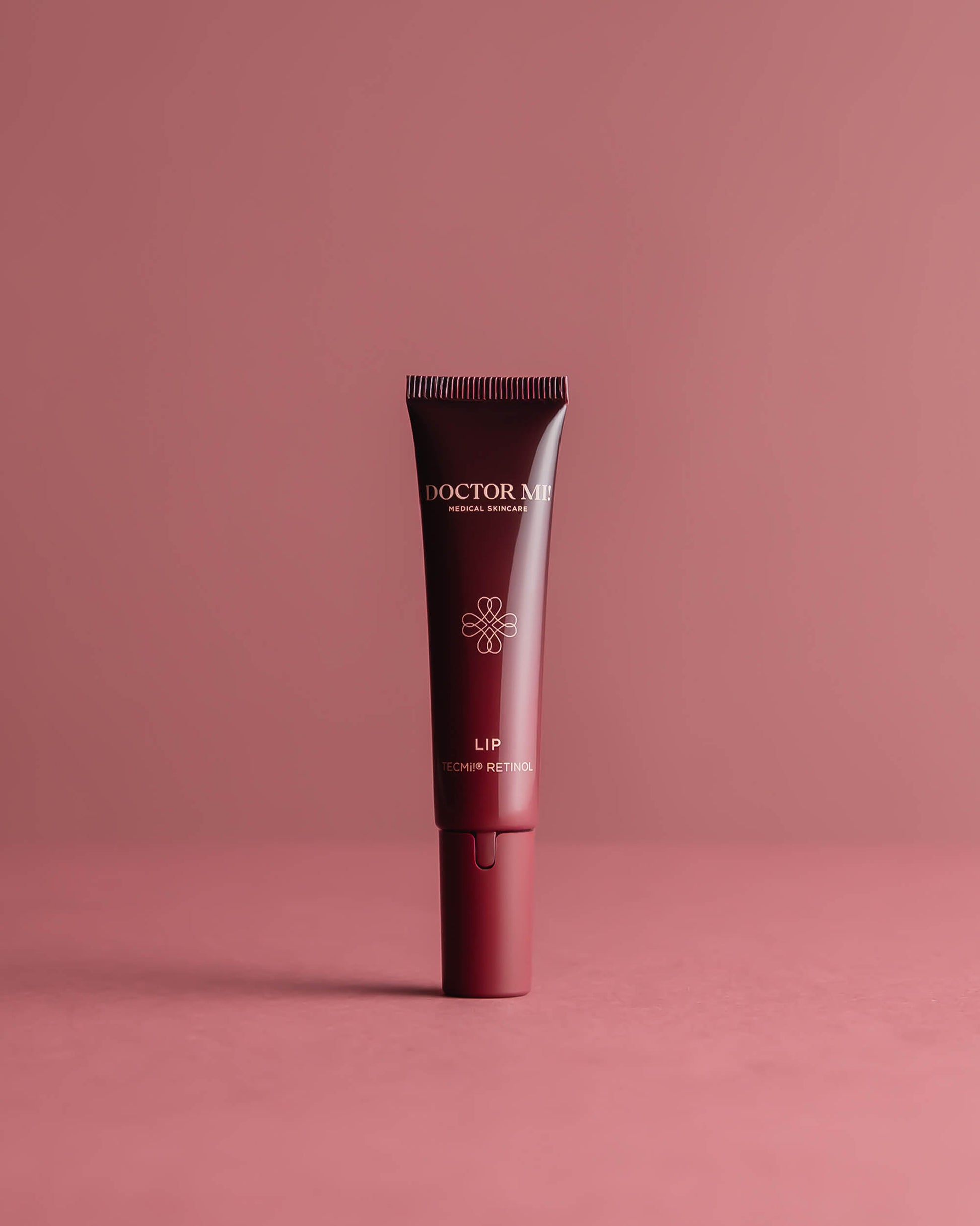 DOCTOR MI! PLUMPING LIP CARE intensive Lippenpflege mit Retinol TECMi!® Technologie für durchfeuchte und voluminöse Lippen in roter Tube auf rotem Hintergrund