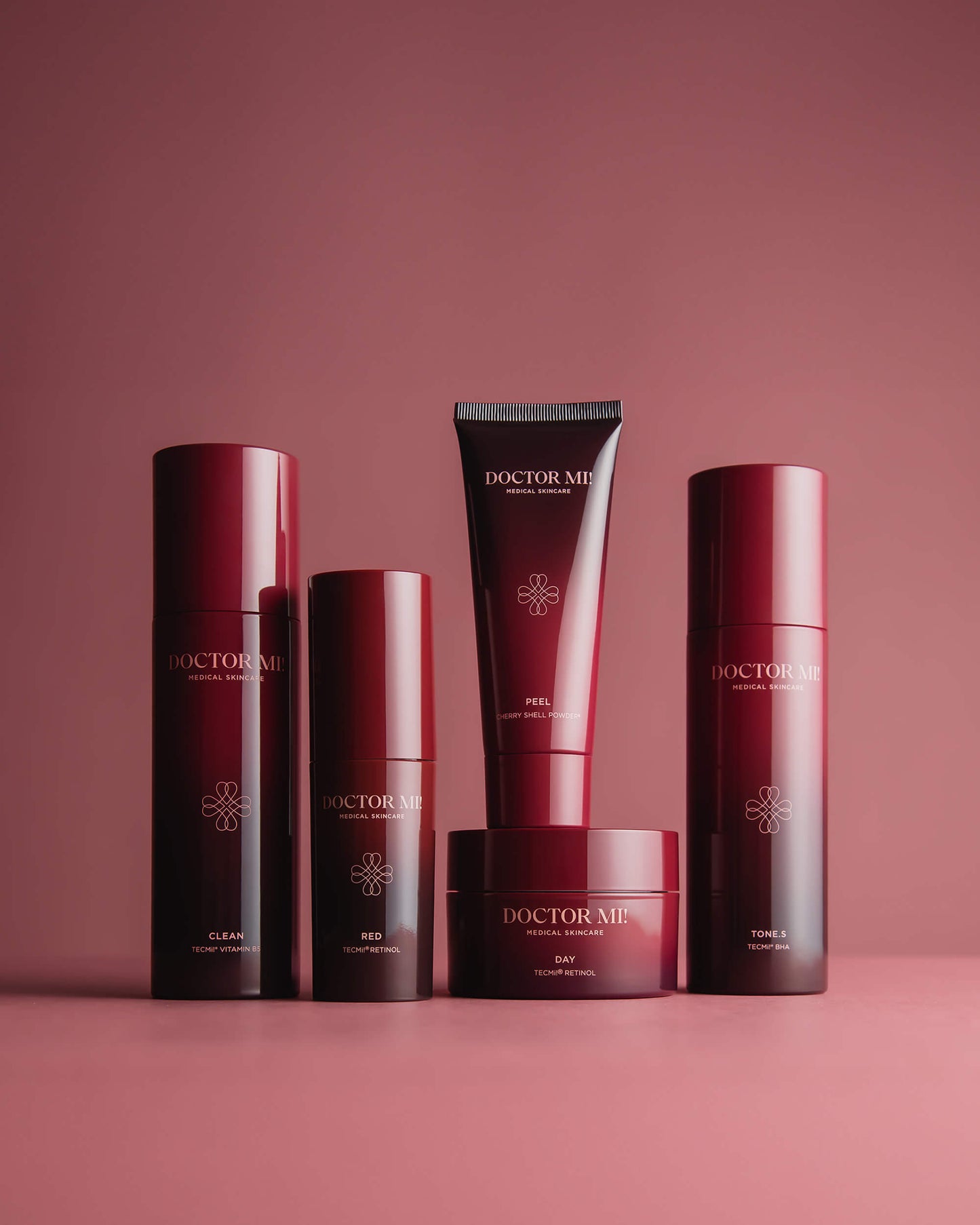 DOCTOR MI! AKNE SET Produktset für zu Akne neigender Haut mit tiefenwirksame und beruhigende Prozesse für ein klares Hautbild dank TECMi!® Retinol mit BALANCING CLEANSER in rotem Pumpspender, REVIVING PEEL in roter Tube, RENEWING TONER in rotem Pumpspender, REFINING DAY CREAM in rotem Tiegel, RED BOOSTER in rotem Pumpspender auf rotem Hintergrund