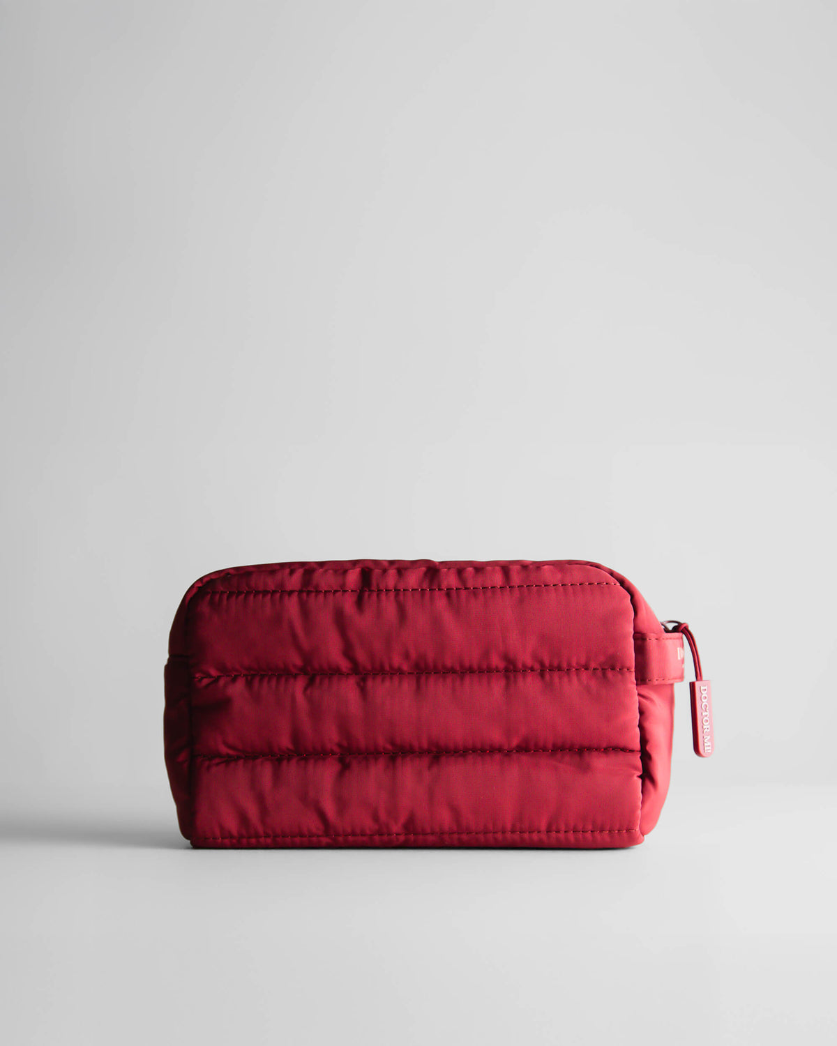 DOCTOR MI! BAG PUFFY RED praktische Kosmetiktasche in roter Steppoptik auf grauem Hintergrund 